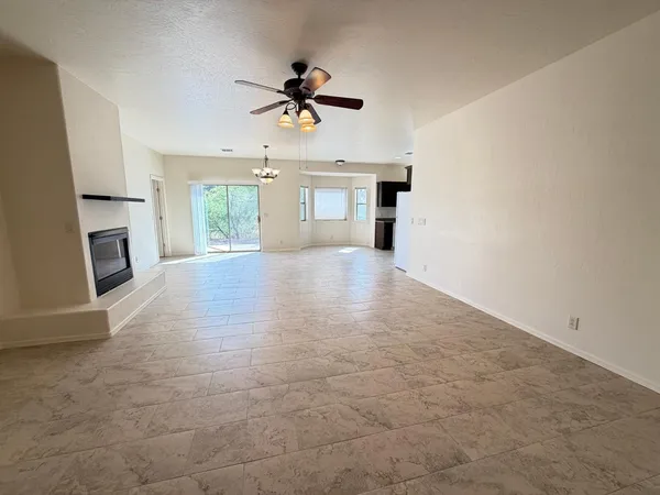 a view of a livingroom with a ceiling fan a fireplace and window