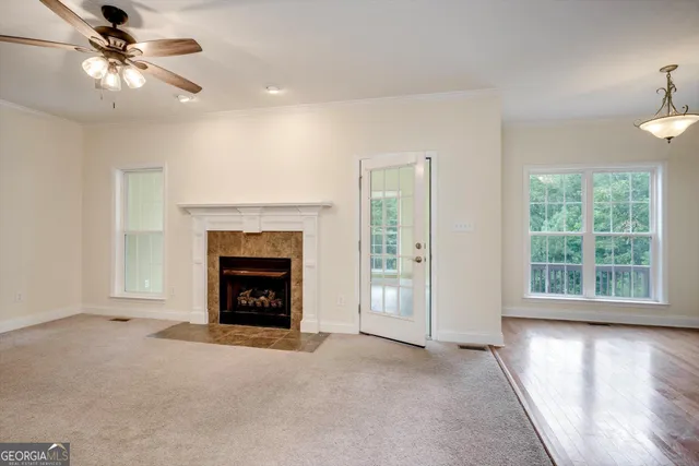 a view of a livingroom with a fireplace a ceiling fan and wooden floor