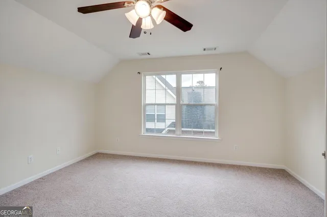 an empty room with a window and a chandelier fan