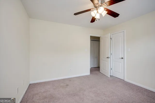 a view of an empty room and chandelier fan