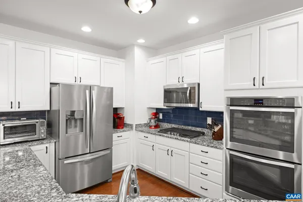 a kitchen with granite countertop a refrigerator stove and microwave