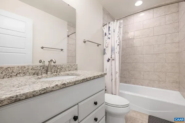 a bathroom with a granite countertop sink a toilet and bathtub