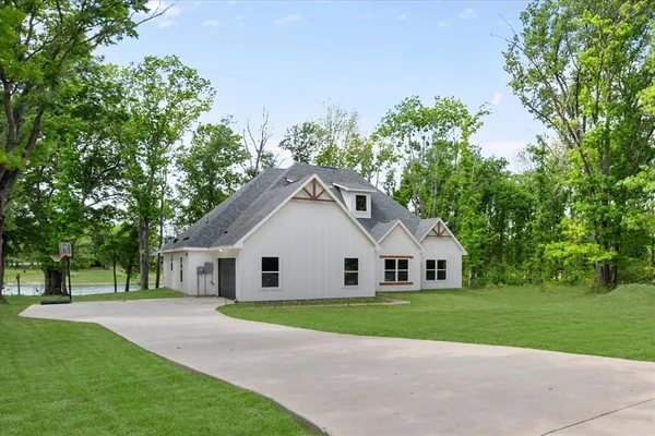 a view of a white house with a big yard and large trees