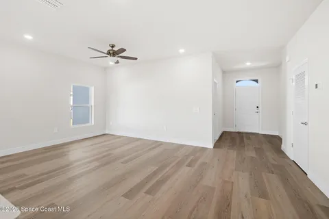 a view of an empty room with a window and wooden floor