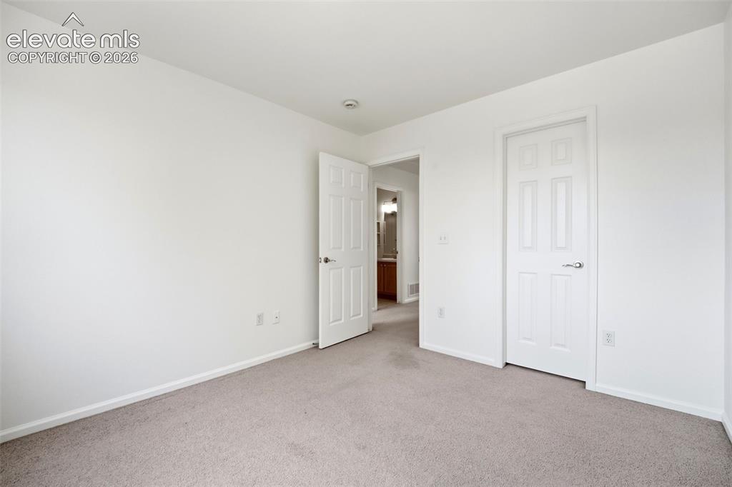 7904 Coffee Road Peyton, CO 80831 - Photo 30 of 48 Carpeted room featuring white walls, white baseboards, and two white paneled doors with silver hardware