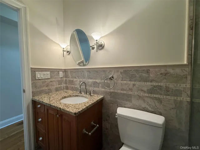 a bathroom with a granite countertop toilet sink and mirror