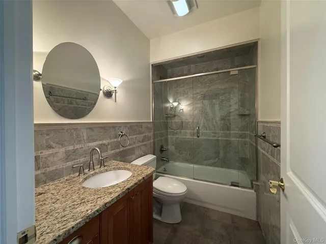 a bathroom with a granite countertop sink a toilet and shower