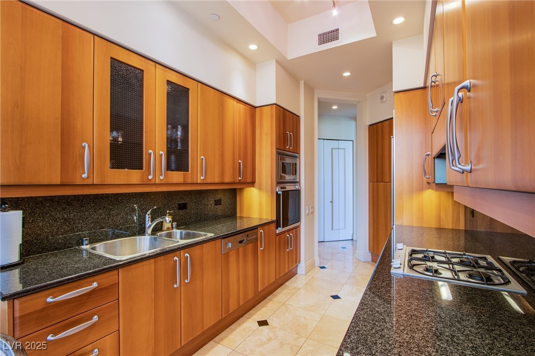 2857 Paradise Road, Unit 206 Las Vegas, NV 89109 - Photo 22 of 31 Kitchen with glass insert cabinets, dark stone countertops, brown cabinetry, recessed lighting, and built in appliances