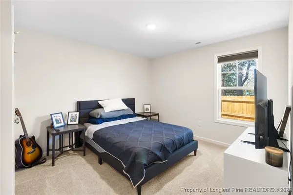 a bedroom with a bed and a flat tv screen on the dresser