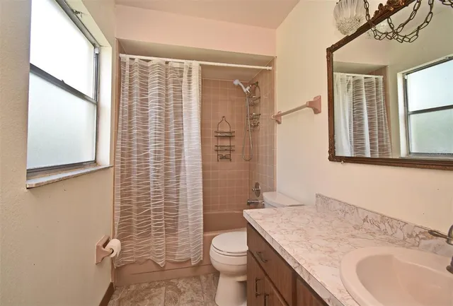 a bathroom with a granite countertop toilet a sink a shower and a mirror