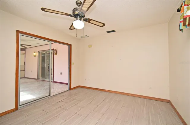 an empty room with wooden floor fan and windows