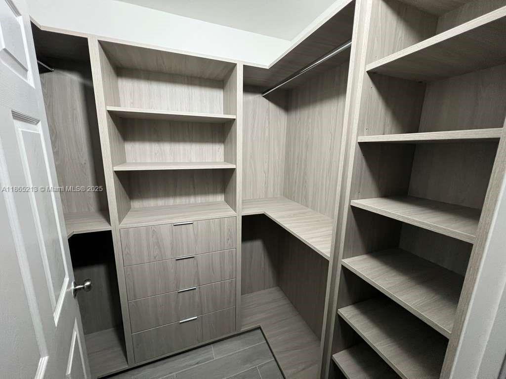 6301 Collins Avenue, Unit 3002 Miami Beach, FL 33141 - Photo 26 of 27 a hallway with cabinets and two wooden floors