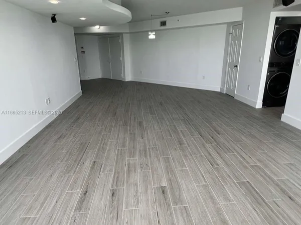 a view of an empty room with wooden floor and closet