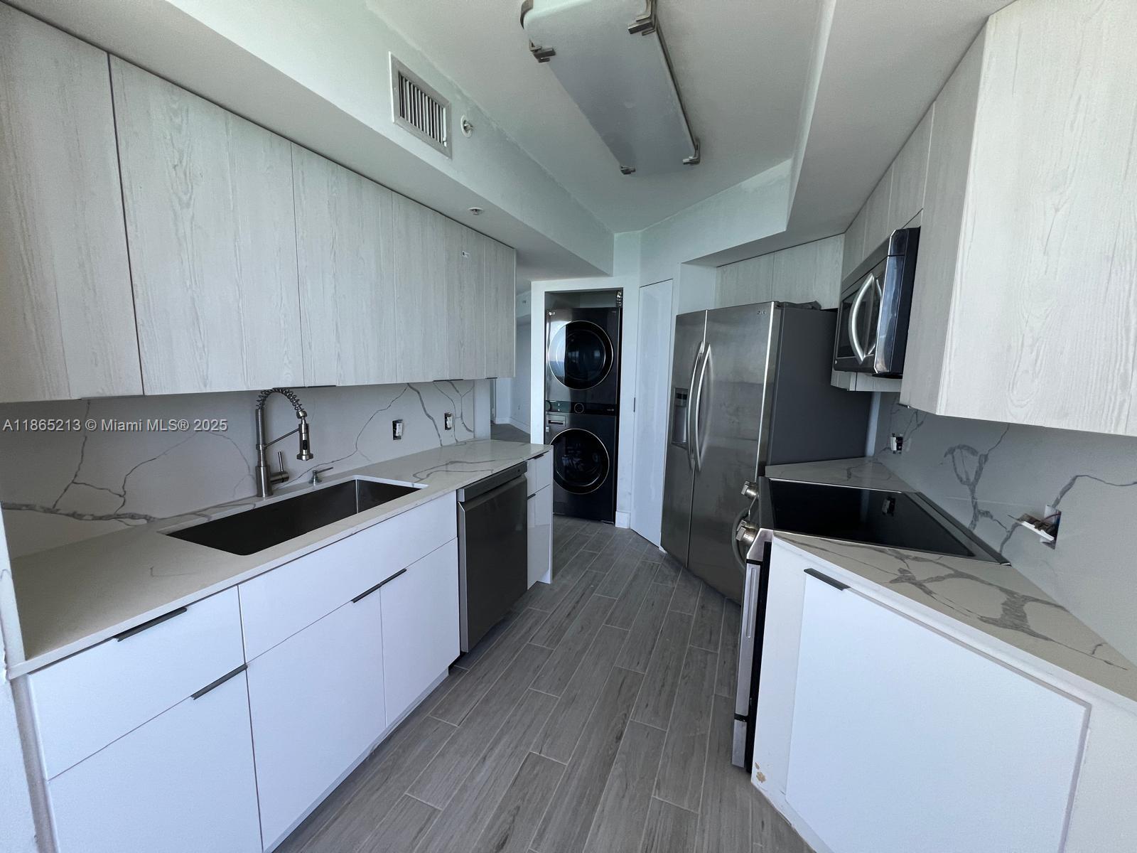 6301 Collins Avenue, Unit 3002 Miami Beach, FL 33141 - Photo 10 of 27 a kitchen with stainless steel appliances a sink dishwasher stove refrigerator and cabinets