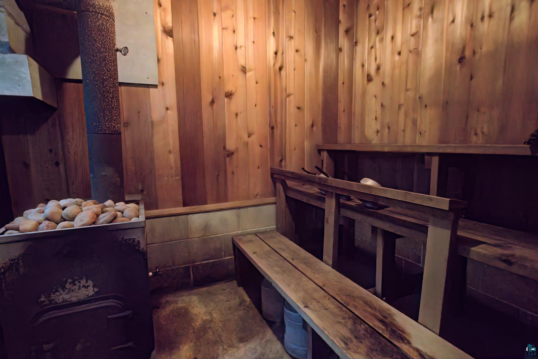 2815 Schaeffer Road Ely, MN 55731 - Photo 26 of 37 Wood-paneled sauna with built-in wooden benches, tile flooring, and a stone heater
