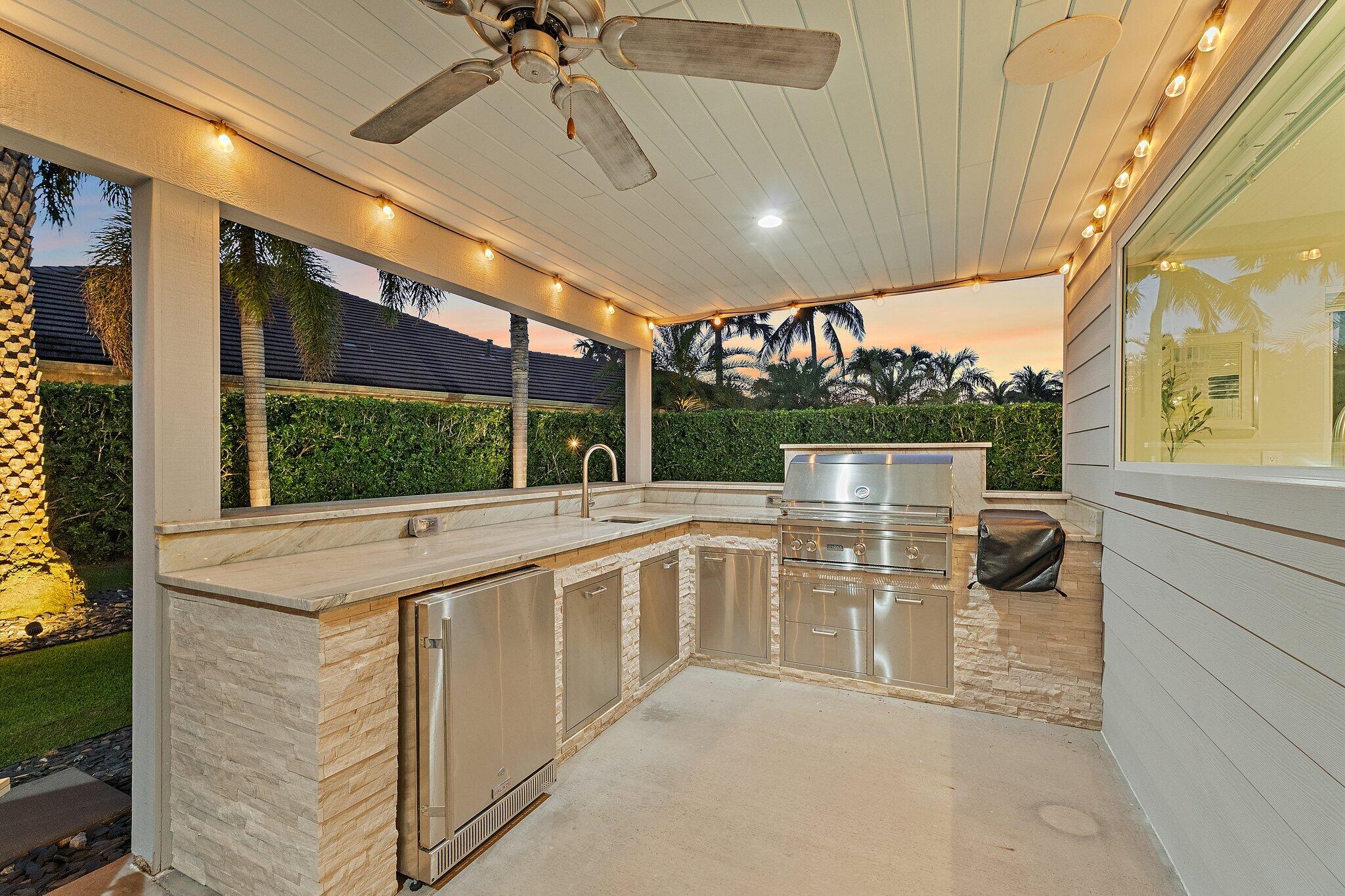 126 Orion Circle Jupiter, FL 33477 - Photo 66 of 82 a view of a patio with a table and chairs under an umbrella with a small yard
