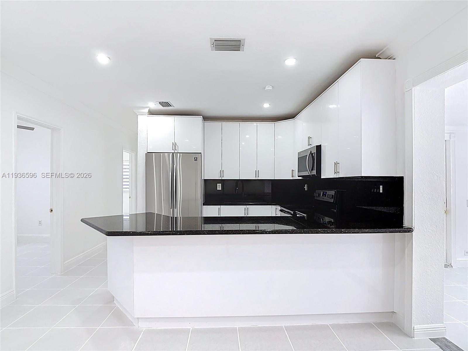 7410 Southwest 39th Street Miami, FL 33155 - Photo 13 of 47 a large kitchen with kitchen island a sink stainless steel appliances and white cabinets