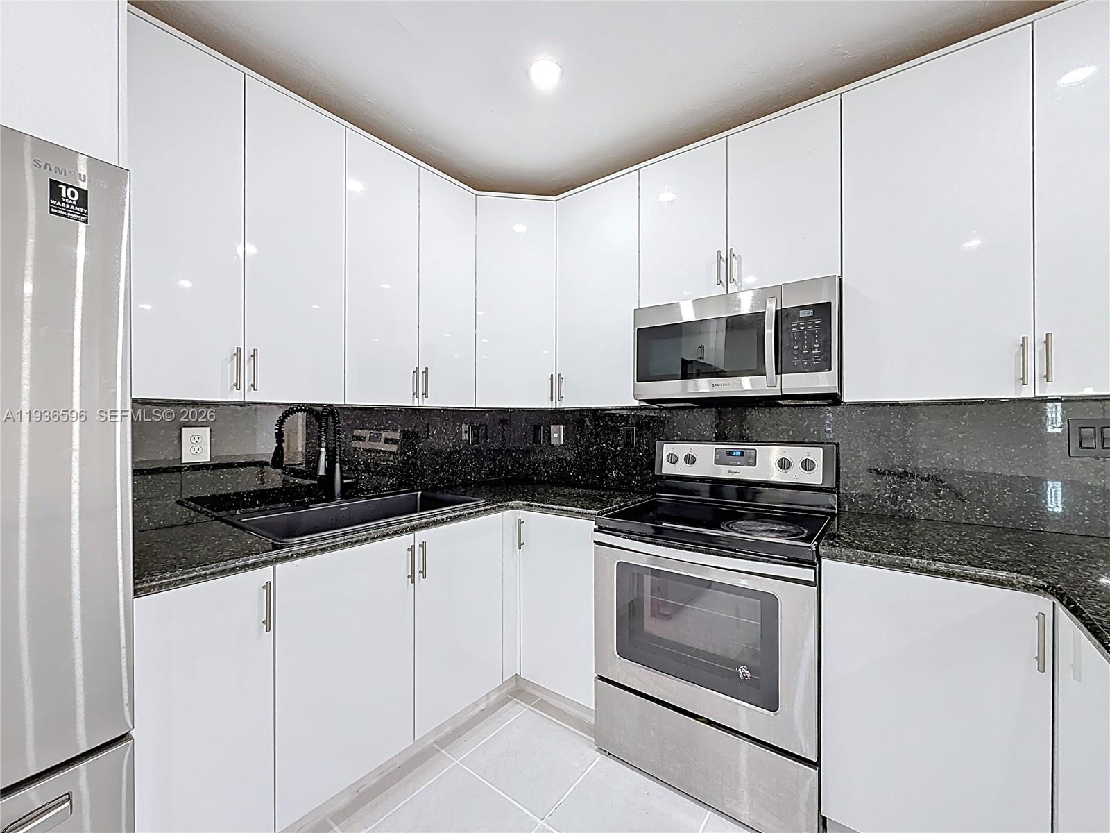 7410 Southwest 39th Street Miami, FL 33155 - Photo 16 of 47 a kitchen with granite countertop white cabinets stainless steel appliances and a sink