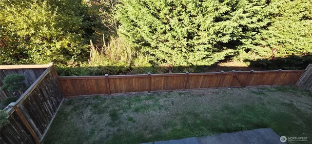 a view of backyard with wooden fence and trees