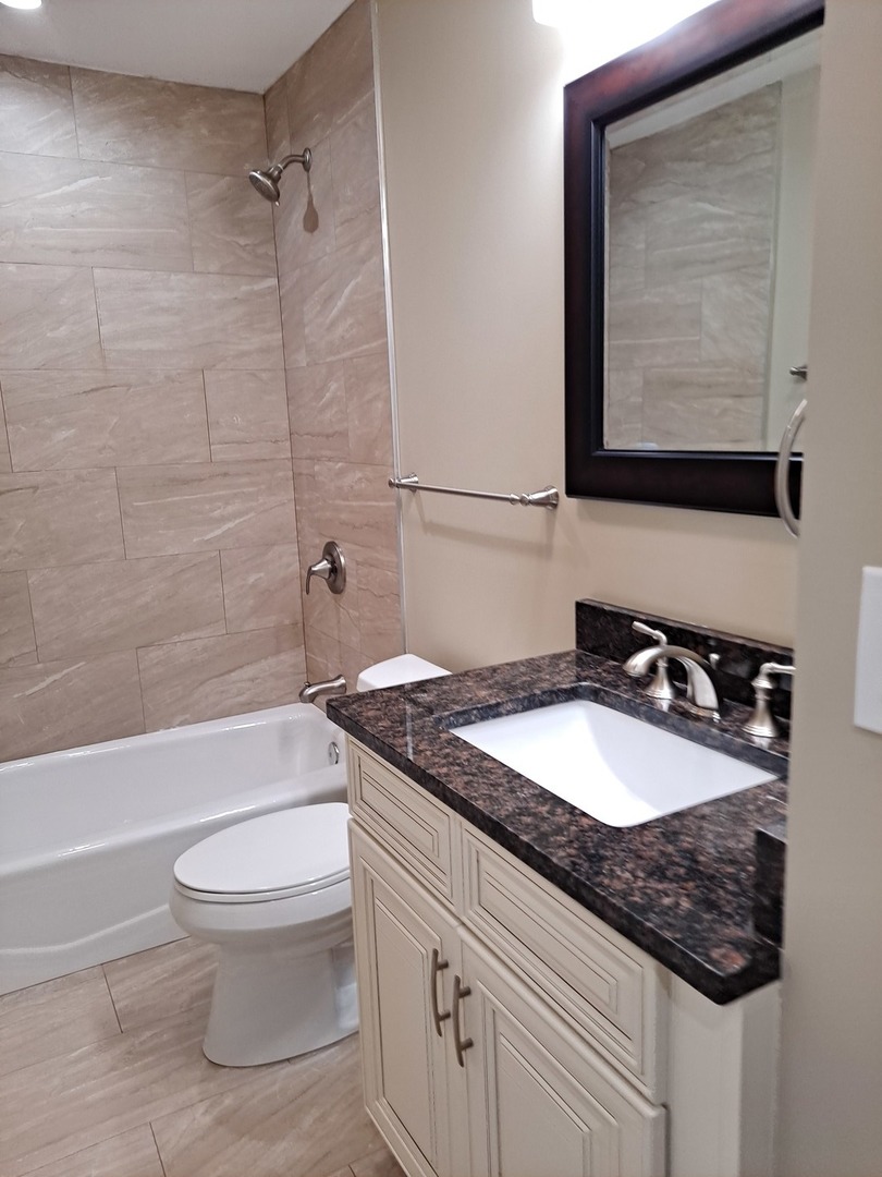 601 West Romeo Road Romeoville, IL 60446 - Photo 14 of 29 a bathroom with a granite countertop sink toilet a mirror and bathtub