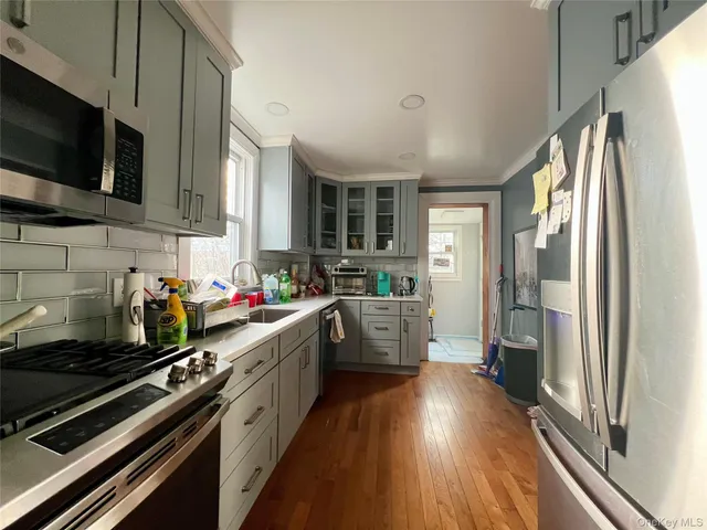 a kitchen with stainless steel appliances a stove a sink dishwasher a refrigerator and a stove with wooden floor