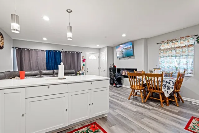 a view of dining room and livingroom with furniture wooden floor a rug a flat screen tv a painting and a chandelier