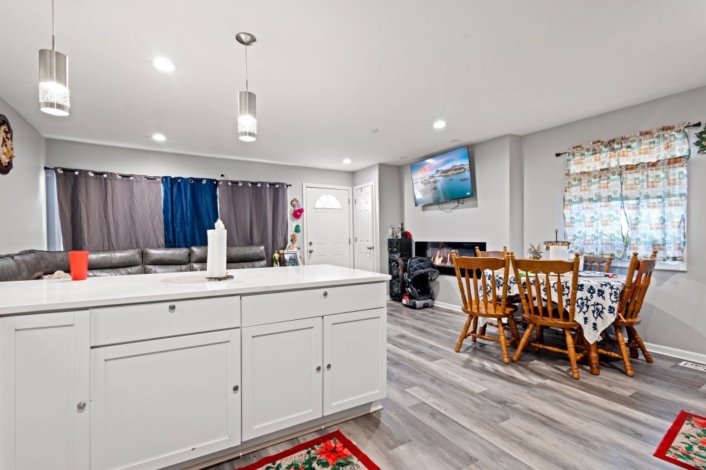 14564 Spaulding Avenue Harvey, IL 60426 - Photo 5 of 20 a view of dining room and livingroom with furniture wooden floor a rug a flat screen tv a painting and a chandelier