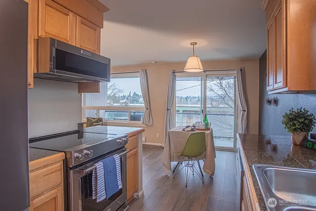 a kitchen with granite countertop a stove a sink a dining table and chairs