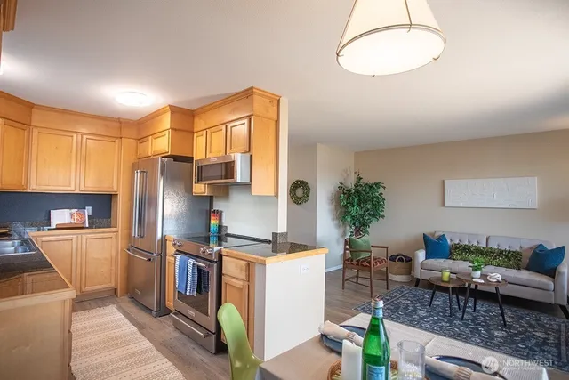 a kitchen with stainless steel appliances a refrigerator a stove a sink a dining table and chairs