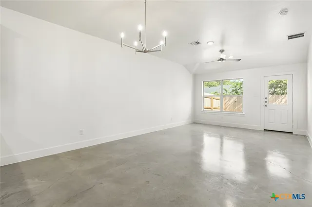 an empty room with windows and chandelier fan