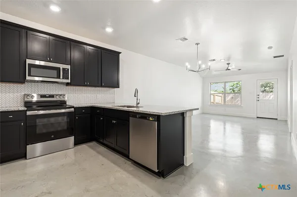 a kitchen with stainless steel appliances granite countertop a stove a sink and a microwave