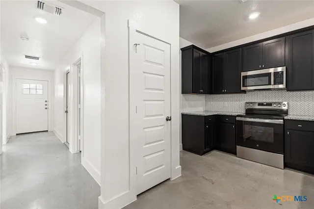 a kitchen with a refrigerator and a stove top oven
