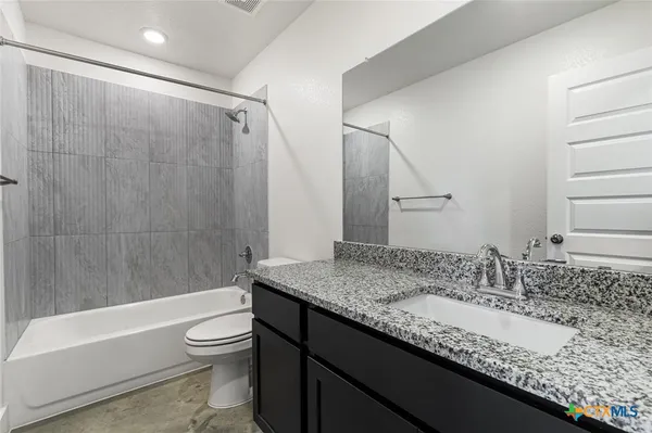 a bathroom with a granite countertop sink a toilet and bathtub