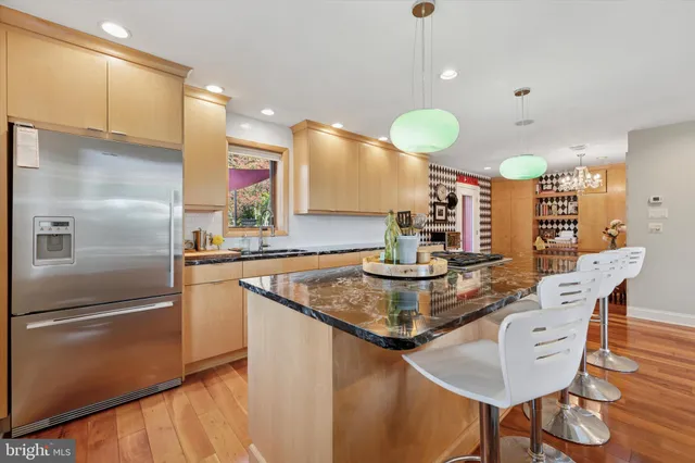 a kitchen with stainless steel appliances granite countertop a sink a refrigerator and a wooden cabinets