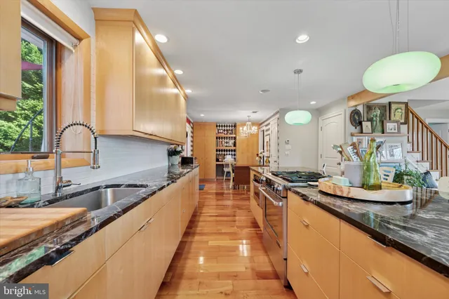 a large kitchen with granite countertop a large counter top a stove a sink and a window