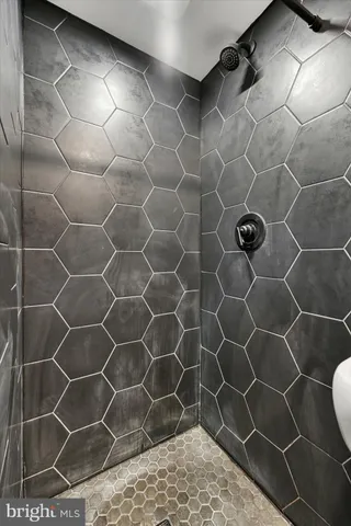 a bathroom with a glass door shower a sink and a blue shower