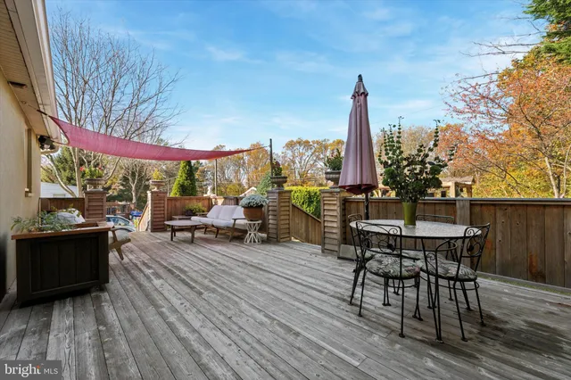 a view of a roof deck with table and chairs couches wooden floor and a yard
