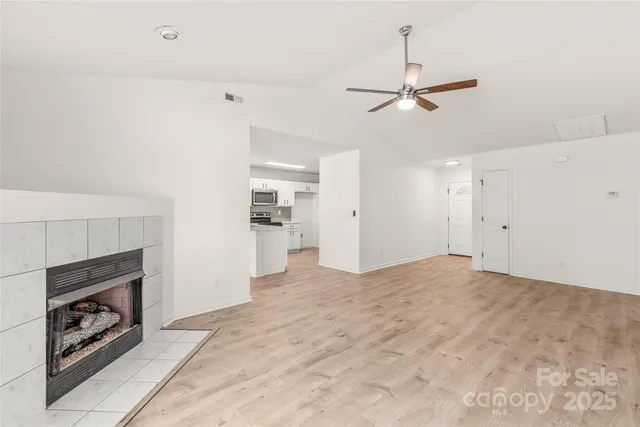 a view of empty room with fireplace and ceiling fan