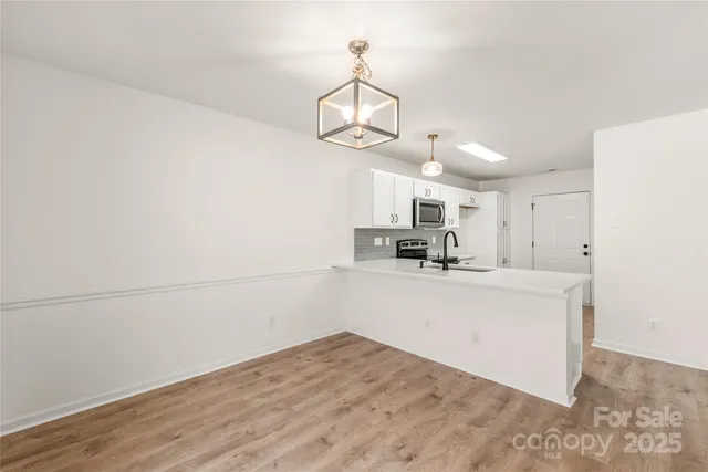 a view of a kitchen with a sink and dishwasher with wooden floor