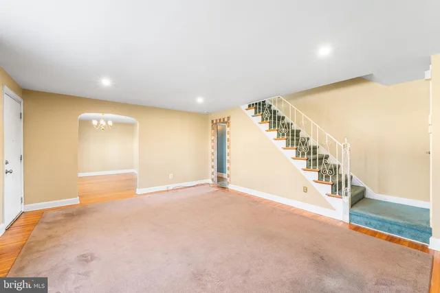 a view of an empty room with stairs and a hall with wooden floor