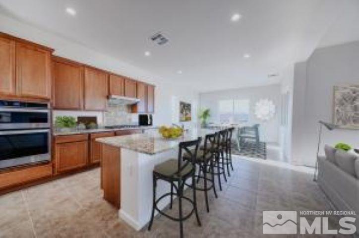9257 Blue Basin Trail, Unit HOMESITE 16 Reno, NV 89521 - Photo 5 of 22 a kitchen with stainless steel appliances kitchen island granite countertop a table chairs sink and cabinets
