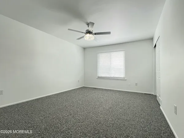 an empty room with a window and a ceiling fan