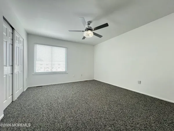 an empty room with a window and a ceiling fan