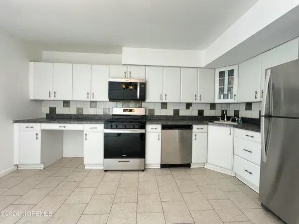 a kitchen with granite countertop white cabinets and refrigerator