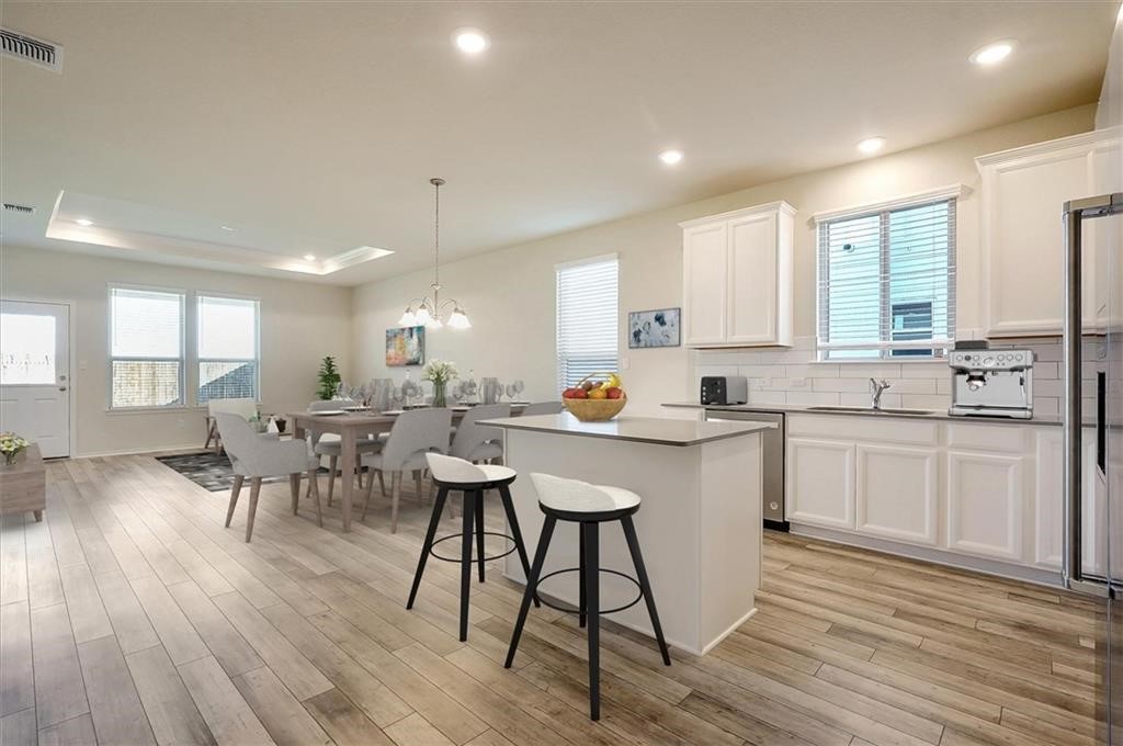 a kitchen with a table chairs wooden floors and white cabinets