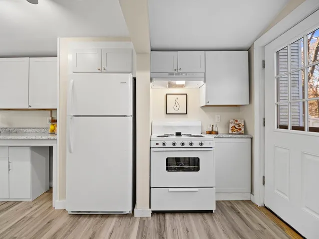 a kitchen with stainless steel appliances granite countertop a refrigerator and white cabinets
