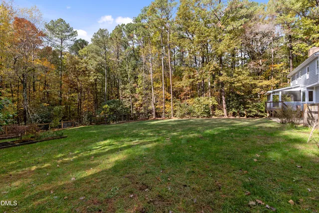 a view of a brick house with a yard plants and large tree