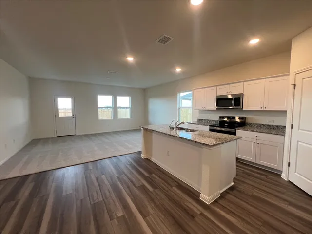 a kitchen with granite countertop a stove top oven and cabinets