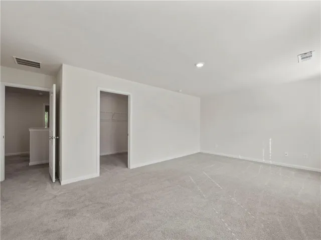a view of an empty room with closet and a bathroom