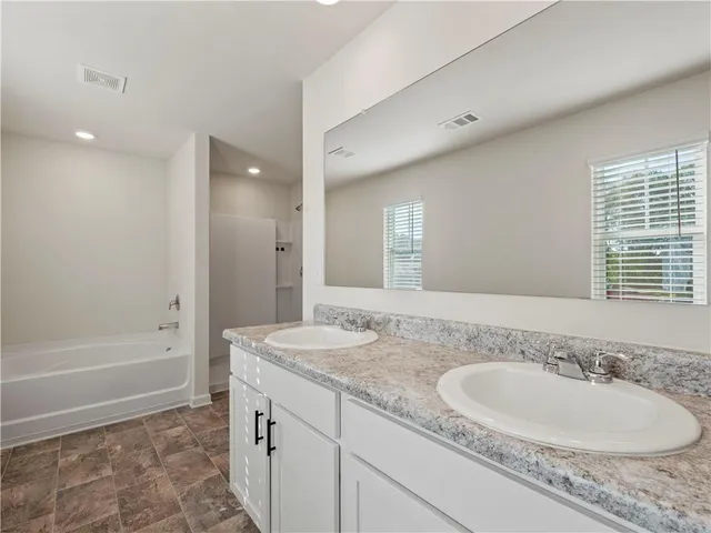 a bathroom with a granite countertop sink and a bathtub